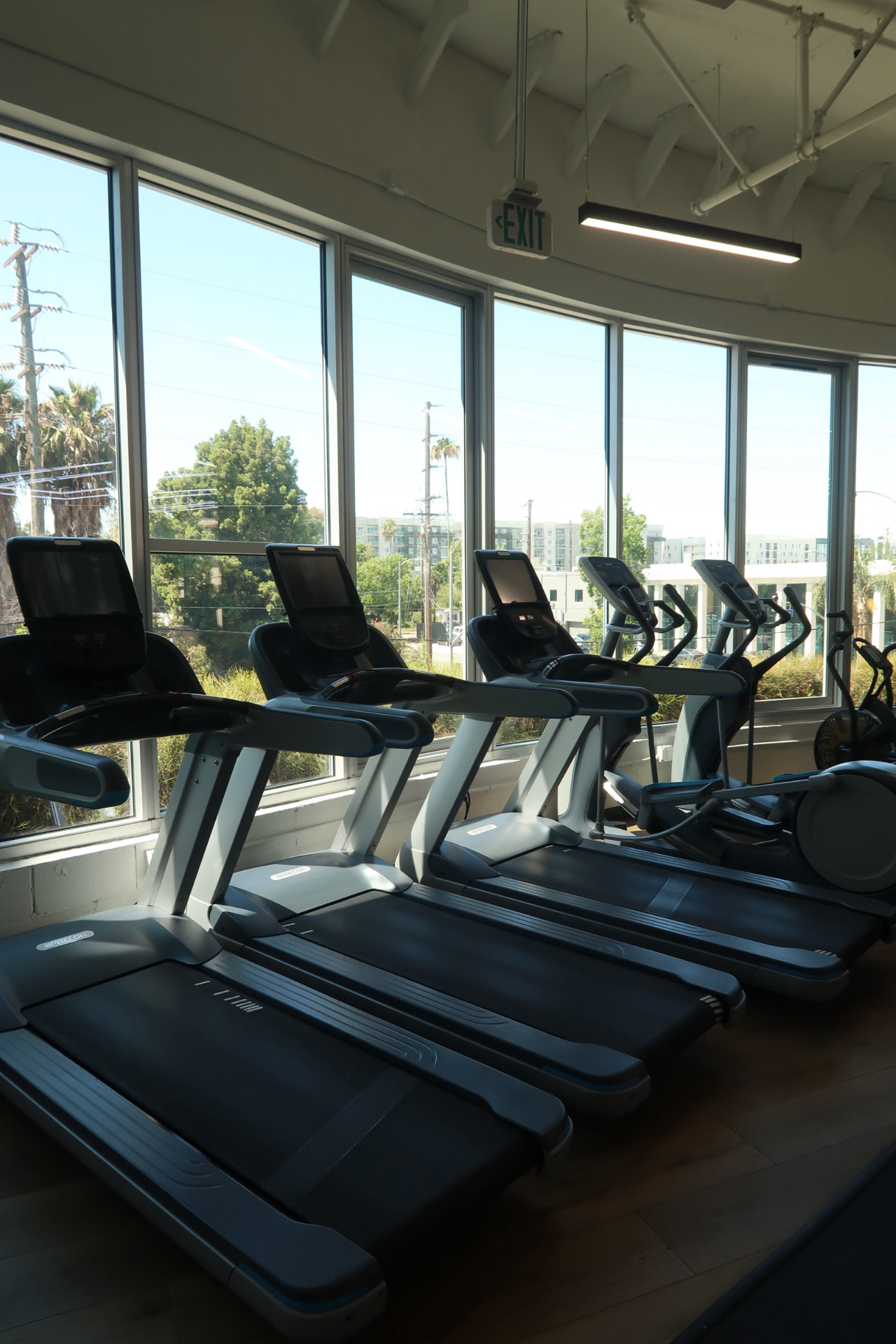 Treadmills and cardio equipment beside floor-to-ceiling windows at Revision.